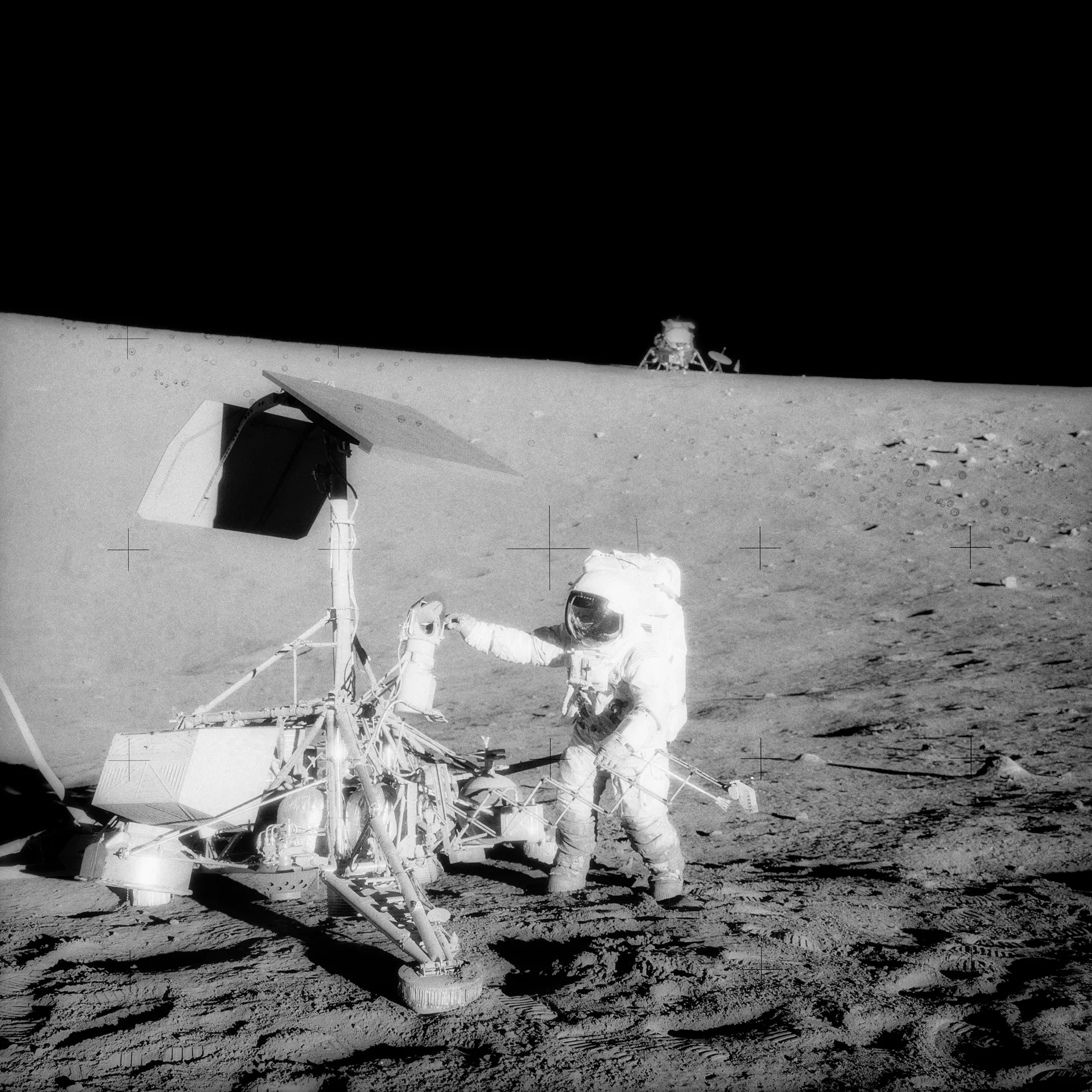 Pete Conrad examines the robotic Surveyor 3 lander, with the Apollo 12 lunar module on the horizon.