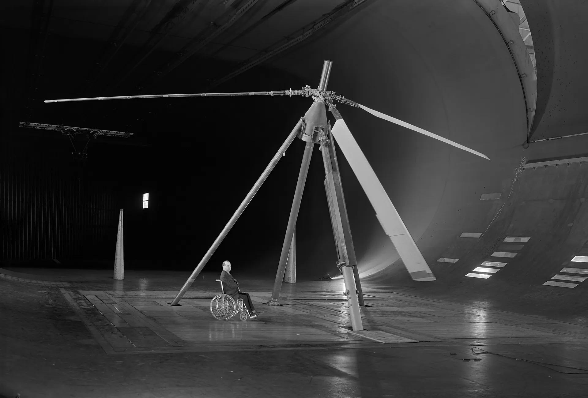 A rotor test rig with long blades stands in the cavernous NACA Ames 40-by-80-foot wind tunnel.