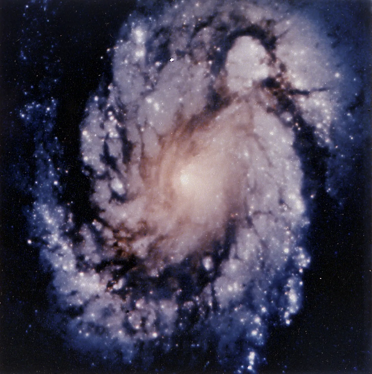 The same spiral galaxy core, now sharp, with individual star clusters and dark dust lanes visible.
