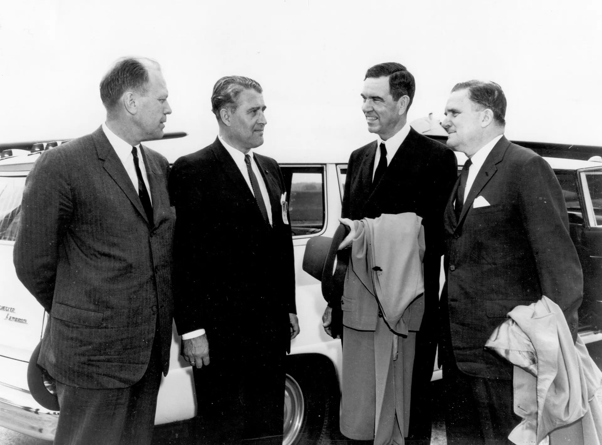 Four men in suits stand by a car at Marshall: Gerald Ford, Wernher von Braun, George Mahon and James Webb.