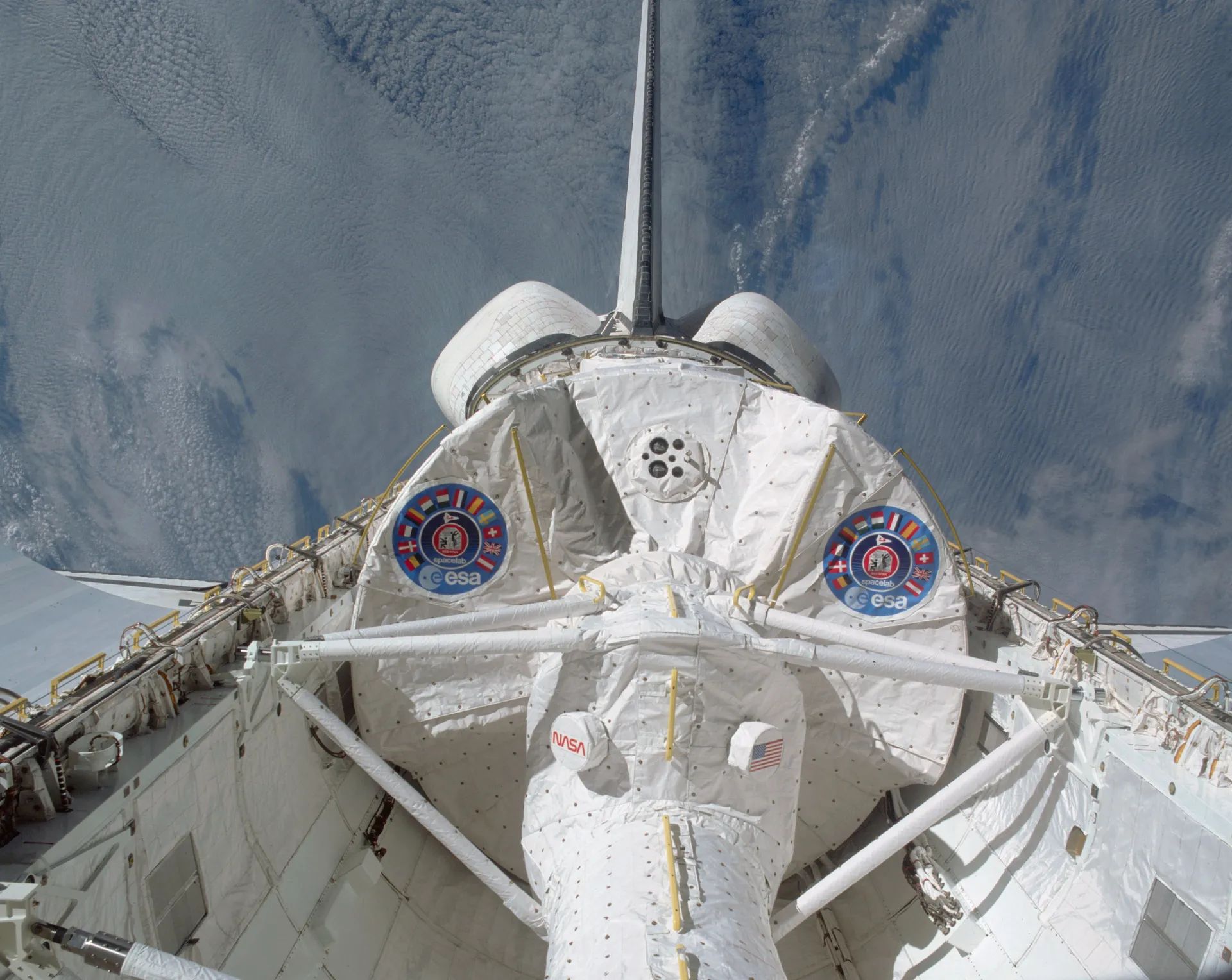 The Spacelab module with ESA markings in Columbia’s open cargo bay, seen through the aft windows, with the ocean beyond.